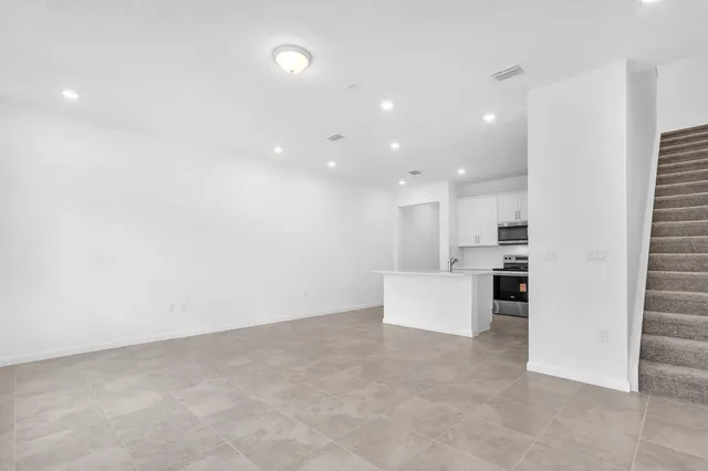 an empty room with kitchen view and a refrigerator