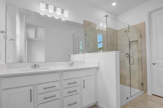 a bathroom with a double vanity sink mirror and shower