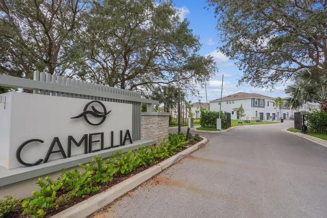 a front view of a house with sign board and a tree