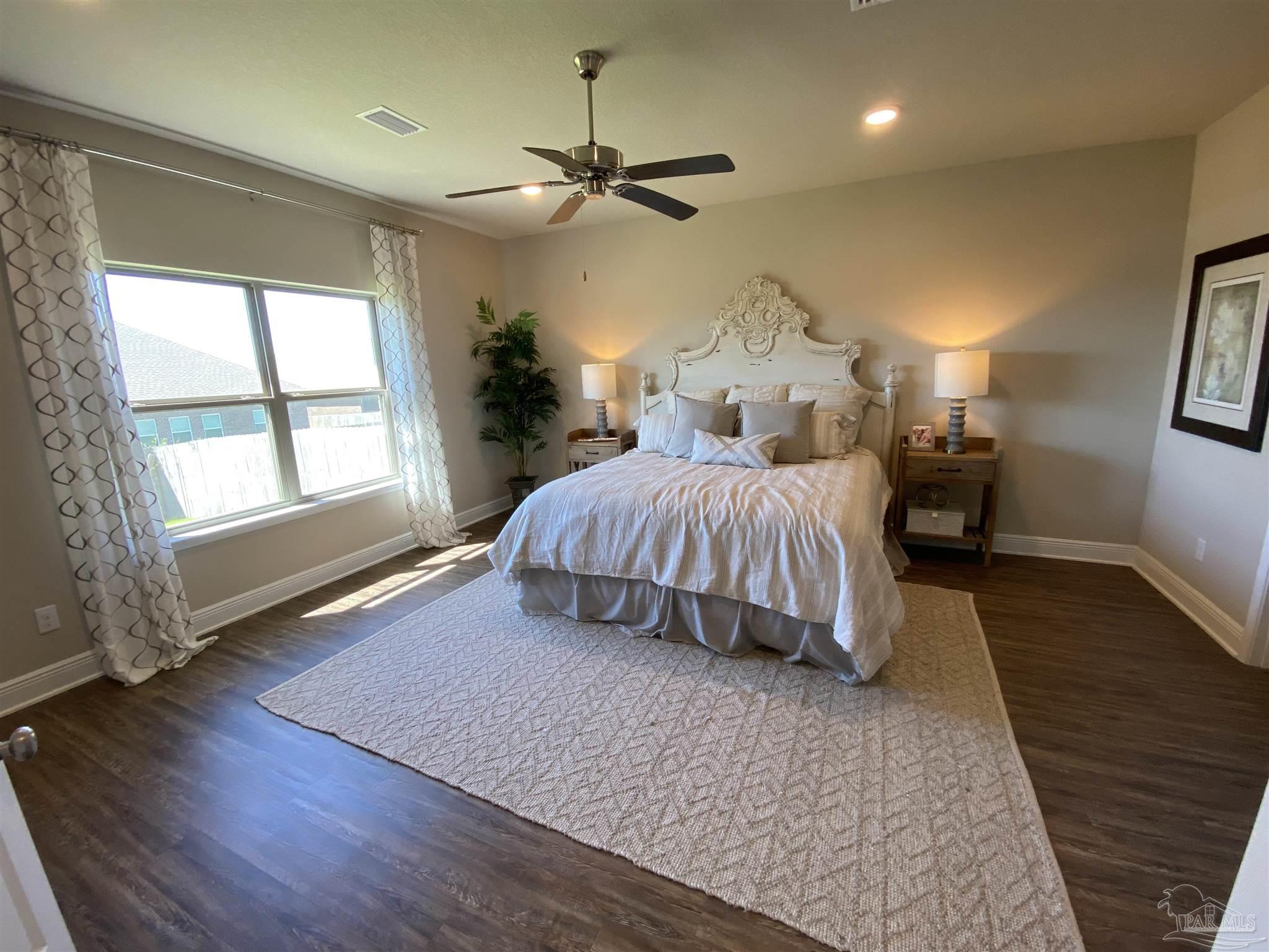7787 Burnside Loop Pensacola, FL 32526 - Photo 11 of 32 a spacious bedroom with a large bed wooden floor and window
