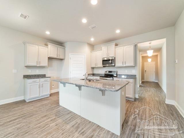 7787 Burnside Loop Pensacola, FL 32526 - Photo 7 of 32 a kitchen with stainless steel appliances granite countertop a sink dishwasher a stove and white cabinets with wooden floor