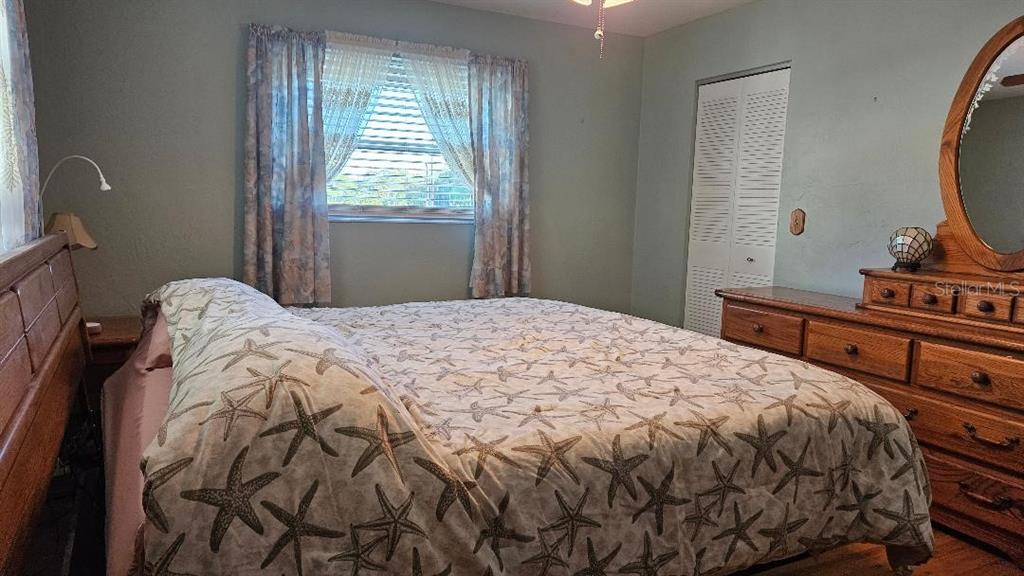 4600 98th Way North, Unit 210 St. Petersburg, FL 33708 - Photo 15 of 33 a bedroom with a bed and a flat tv screen on a dresser