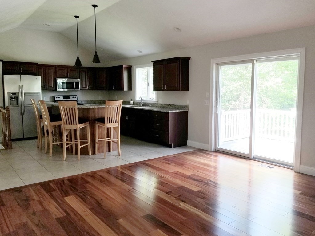 7 Dean Farm Road Sutton, MA 01590 - Photo 24 of 33 a open kitchen with stainless steel appliances granite countertop a stove top oven a sink dishwasher a dining table and chairs with wooden floor