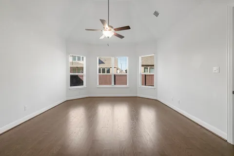 a view of an empty room with window and wooden floor