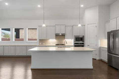 a kitchen with stainless steel appliances a sink a stove a refrigerator and cabinets
