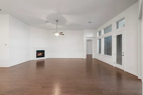 a view of an empty room with chandelier fan and fire place