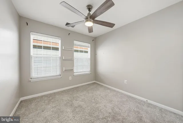 an empty room with windows and ceiling fan