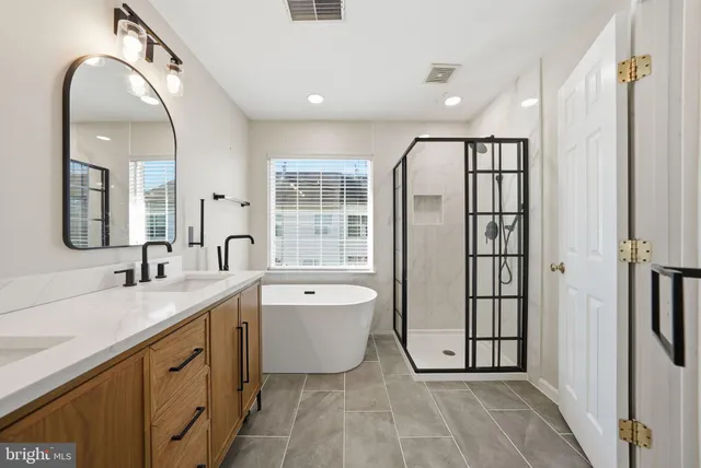a spacious bathroom with a double vanity sink a mirror and a bathtub