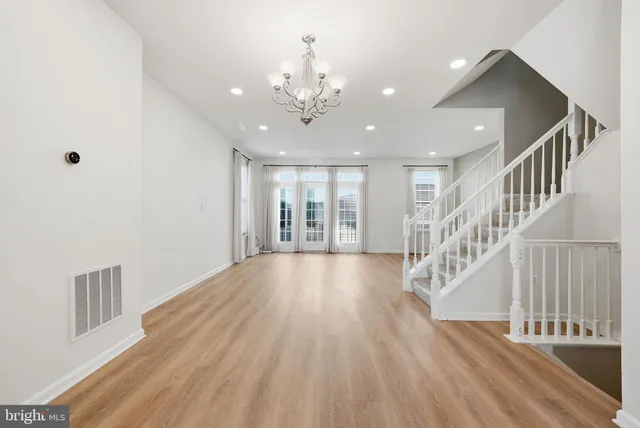 a view of an empty room with wooden floor and staircase