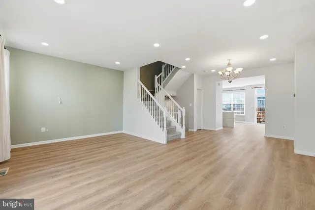 a view of an empty room with wooden floor and stairs