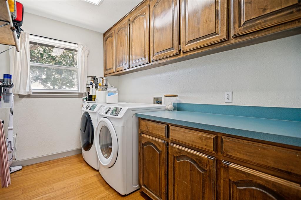 5643 West Caylor Road Fort Worth, TX 76244 - Photo 27 of 37 Large Laundry area featuring wood-finish flooring, a double window, overhead wood cabinetry, and a countertop with additional wood base cabinets