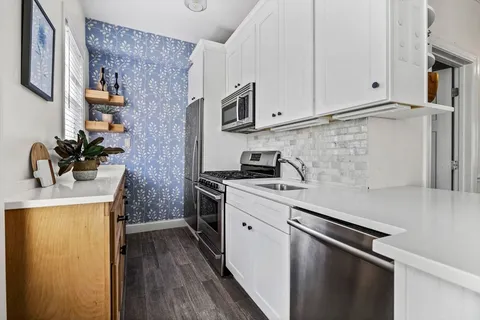 a kitchen with stainless steel appliances a sink stove and cabinets