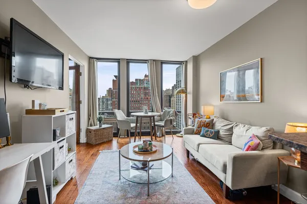 a living room with furniture a flat screen tv and floor to ceiling window