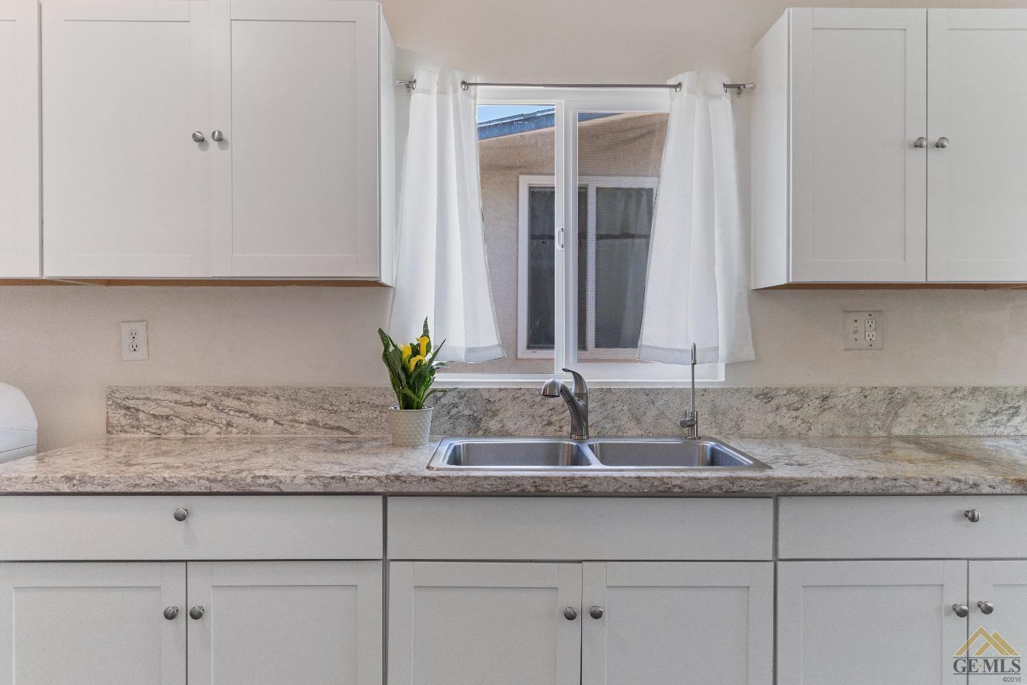 Undisclosed Address Bakersfield, CA 93305 - Photo 23 of 33 a kitchen with granite countertop a sink and white cabinets