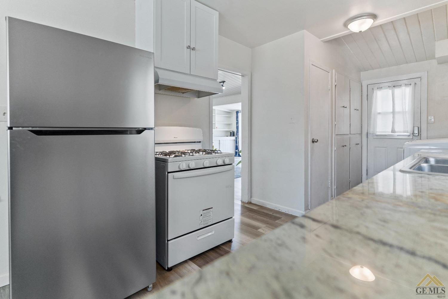 Undisclosed Address Bakersfield, CA 93305 - Photo 28 of 33 a kitchen with a refrigerator a stove and white cabinets