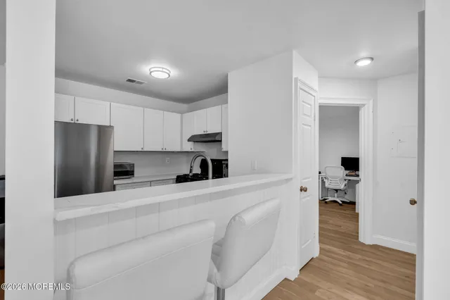 a kitchen with stainless steel appliances kitchen island a refrigerator sink and white cabinets