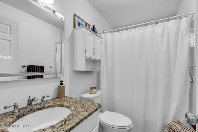 a bathroom with a granite countertop sink toilet and shower