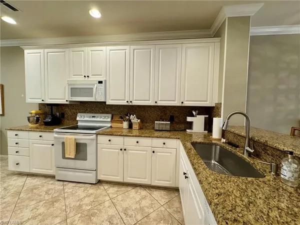 a large kitchen with granite countertop a sink stainless steel appliances and cabinets