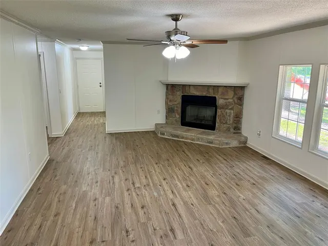 a view of an empty room with wooden floor fireplace and a window