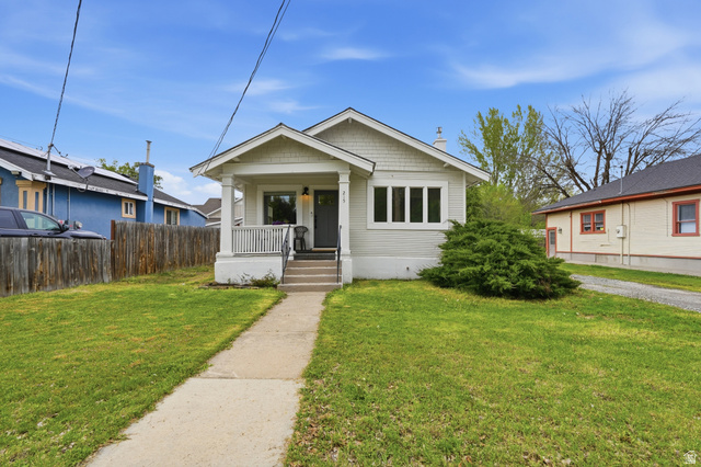 Bungalow featuring covered porch and a front yard
