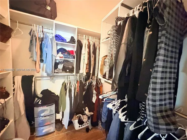 a view of walk in closet with clothes and shoes