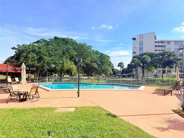 a view of swimming pool with lawn chairs and plants