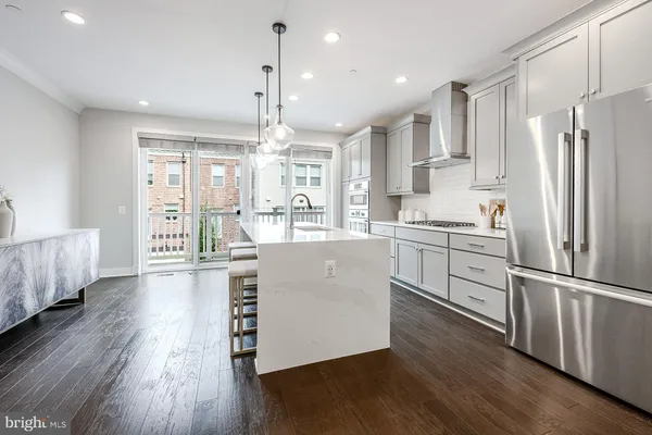 a kitchen with stainless steel appliances granite countertop a refrigerator a sink dishwasher a stove and white cabinets with wooden floor