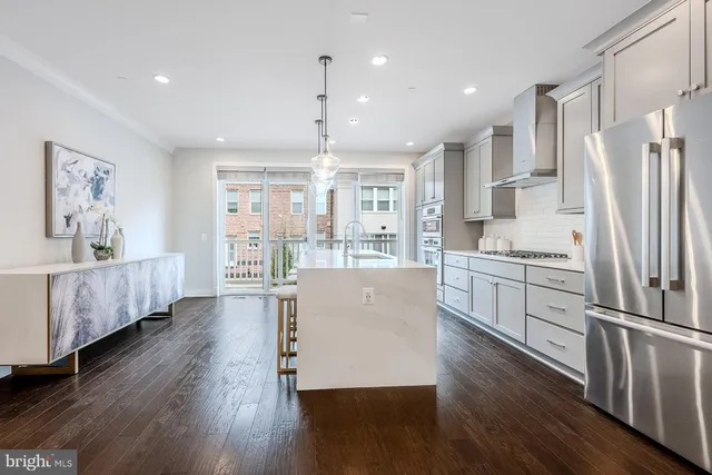 a kitchen with stainless steel appliances granite countertop a refrigerator a sink dishwasher a stove and white cabinets with wooden floor