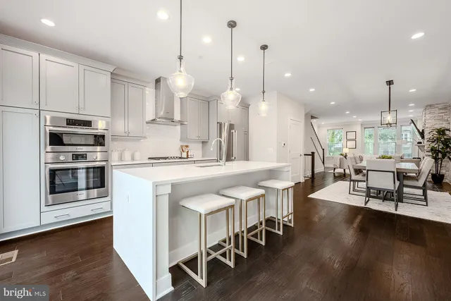a large kitchen with kitchen island a dining table chairs and a wooden floor