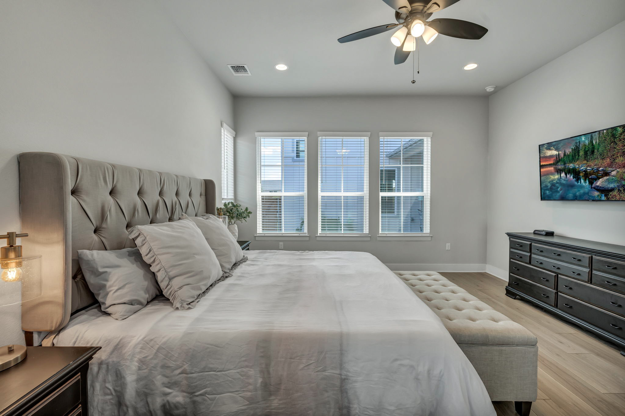 7808 Chrysler Bend Austin, TX 78744 - Photo 14 of 35 Spacious sleeping quarters featuring light wood-finish flooring, a contemporary ceiling fan, recessed lighting, and three large windows