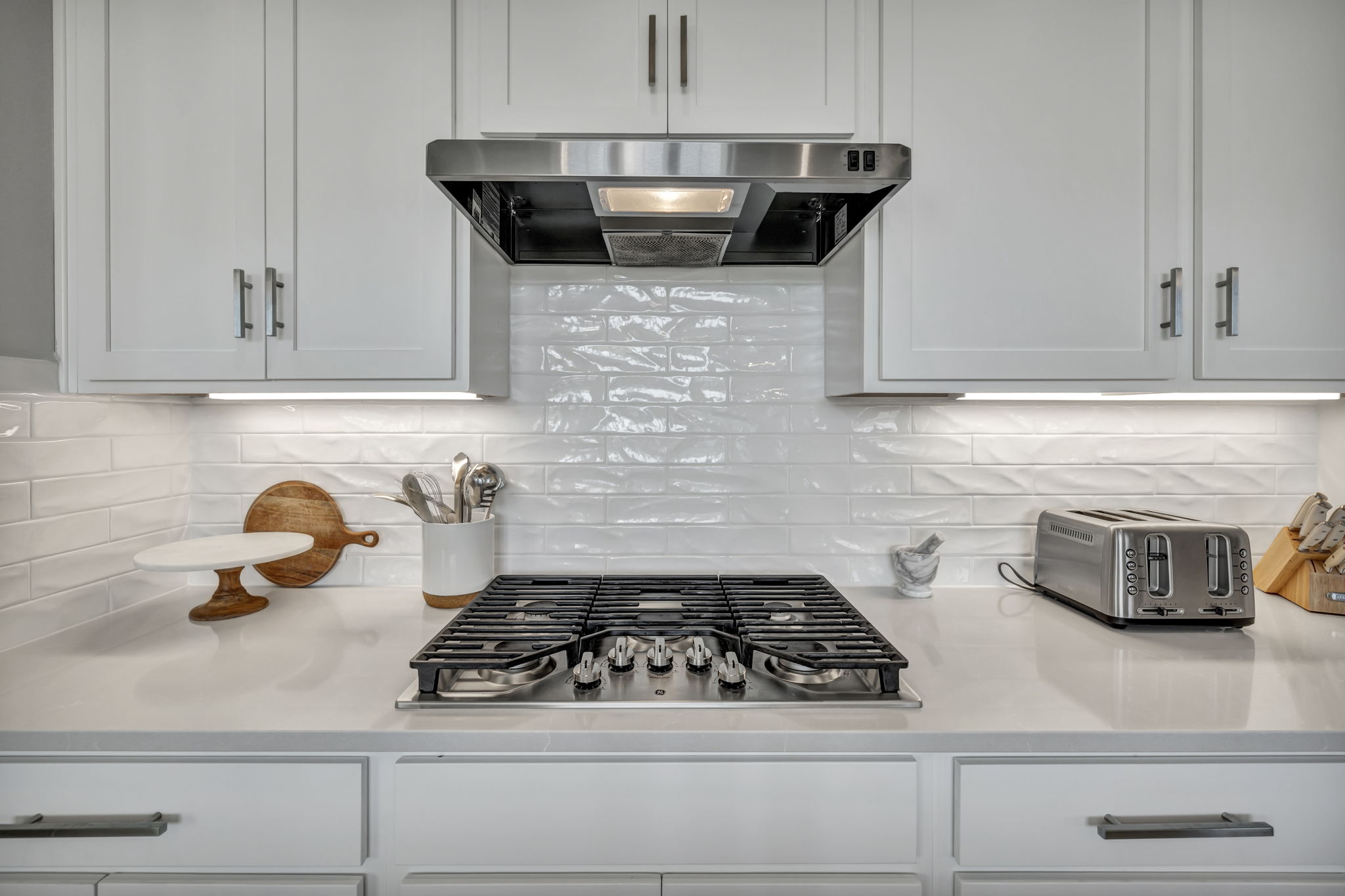 7808 Chrysler Bend Austin, TX 78744 - Photo 6 of 35 Built-in gas cooktop with stainless steel range, subway tile backsplash and quartz countertops