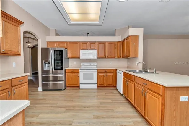 a kitchen with stainless steel appliances kitchen island granite countertop a sink and wooden cabinets