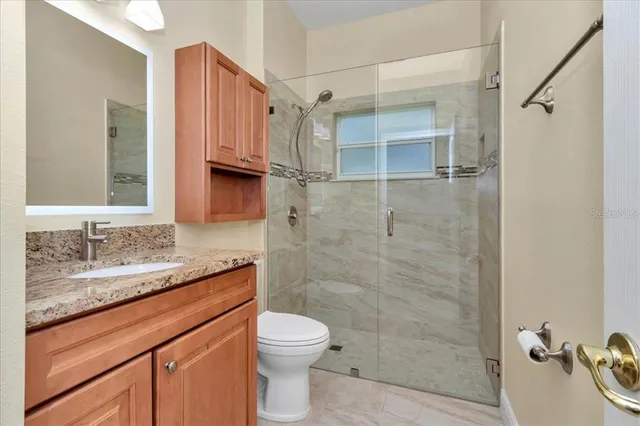 a bathroom with a granite countertop sink toilet and shower