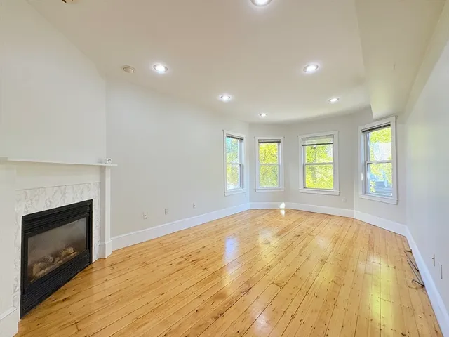 a view of empty room with wooden floor and fireplace