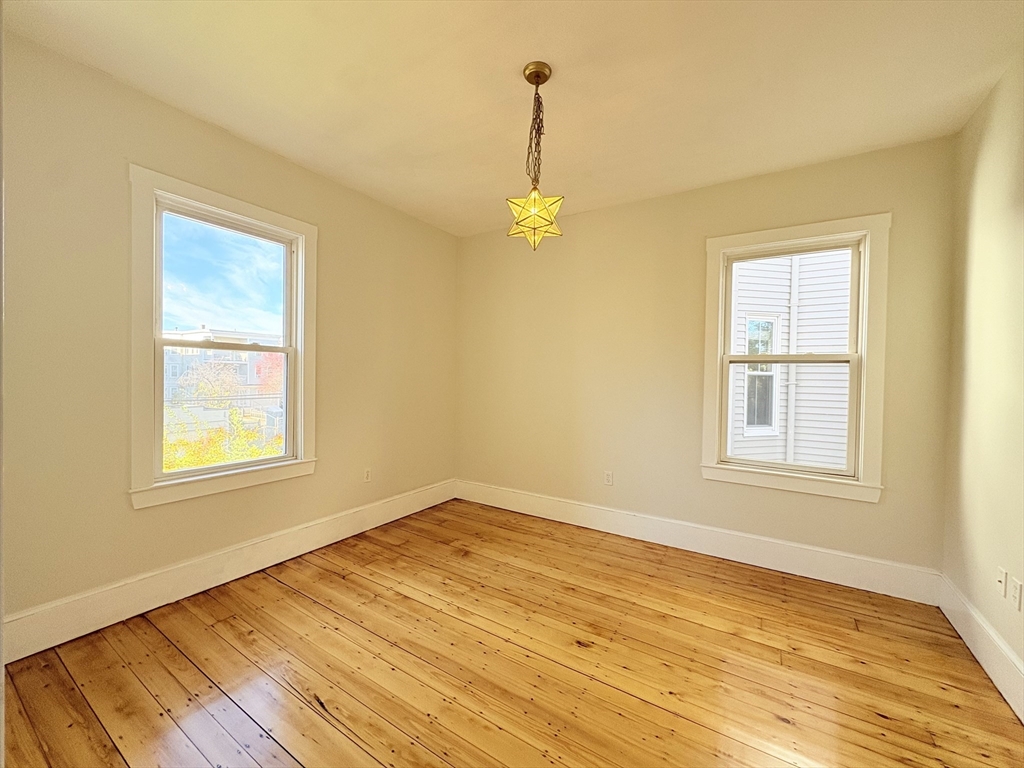 367 Cardinal Medeiros Avenue, Unit 1 Cambridge, MA 02141 - Photo 3 of 8 a view of an empty room with wooden floor and a window