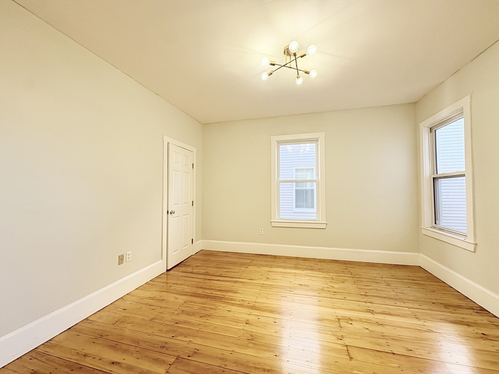 367 Cardinal Medeiros Avenue, Unit 1 Cambridge, MA 02141 - Photo 4 of 8 a view of an empty room with wooden floor and a window