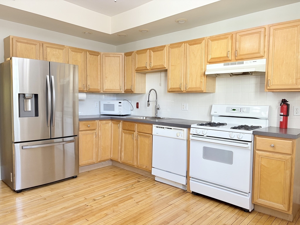 367 Cardinal Medeiros Avenue, Unit 1 Cambridge, MA 02141 - Photo 5 of 8 a kitchen with stainless steel appliances granite countertop a refrigerator sink and cabinets