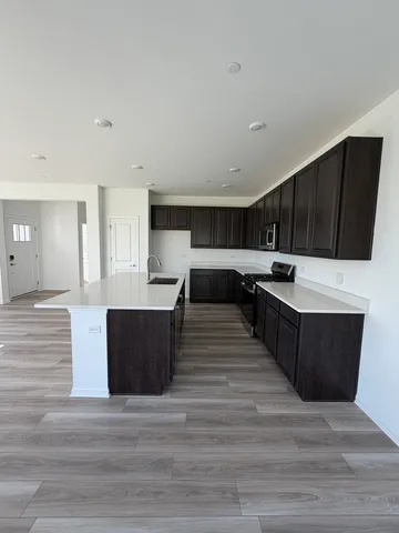 a large kitchen with wooden floors stainless steel appliances a stove and cabinets