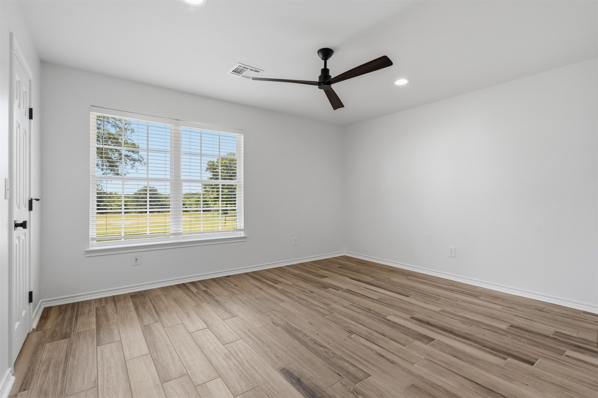 831 Barrons Ridge Wilson, OK 73463 - Photo 26 of 47 Spacious room featuring wood-finish flooring, a large window with blinds, a modern ceiling fan, and recessed lighting