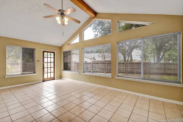 a view of an empty room with a window and a kitchen area
