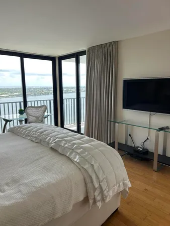 a bedroom with a bed and a flat tv screen next to a large window