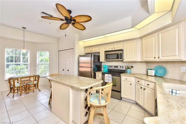 a kitchen filled with white cabinets appliances and a dining table