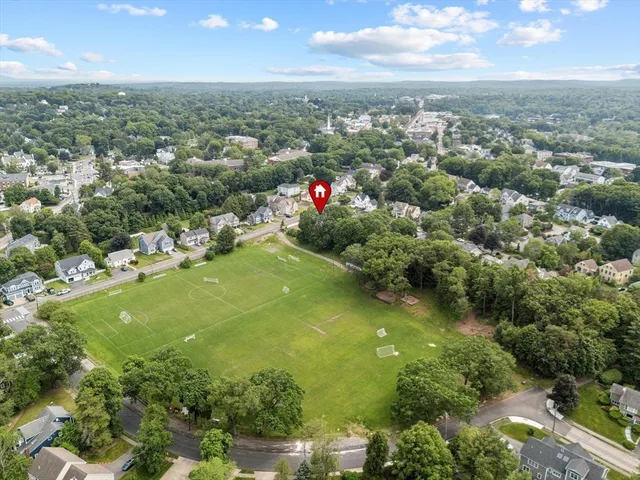 an aerial view of residential houses with outdoor space and trees