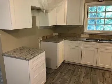 a kitchen with granite countertop white cabinets and sink