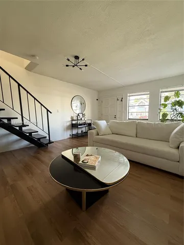 a living room with furniture a couch and a dining table with wooden floor