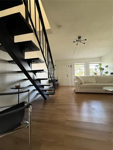 a view of a livingroom with furniture stairs and a window