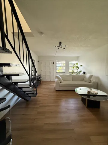 a living room with couches and a dining table with wooden floor