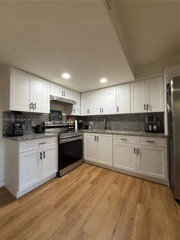 a kitchen with granite countertop white cabinets and white appliances