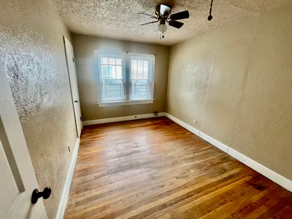 a view of an empty room with a window and wooden floor