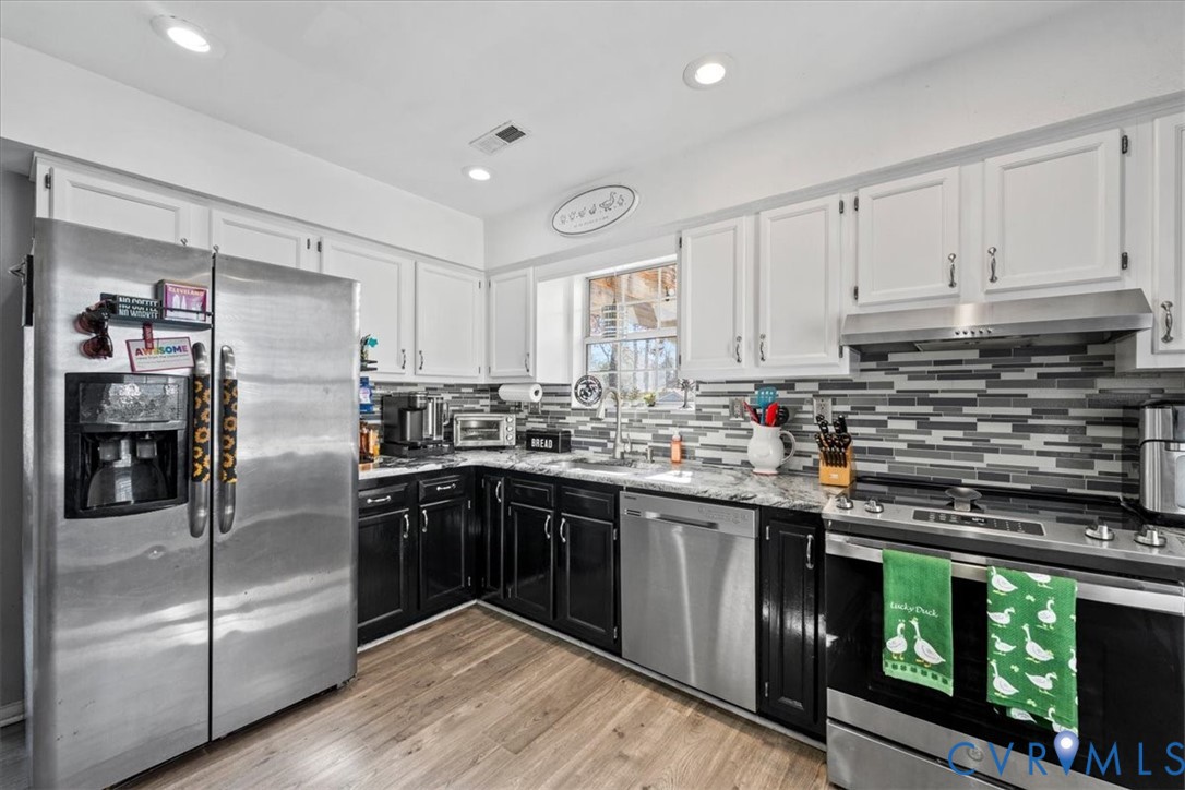 14126 Bermuda Point Court Chester, VA 23836 - Photo 33 of 50 a kitchen with stainless steel appliances granite countertop a refrigerator a sink a stove and white cabinets